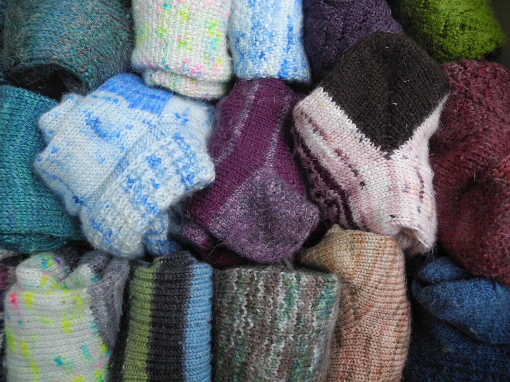 a variety of hand knit socks grouped together in many colors. 