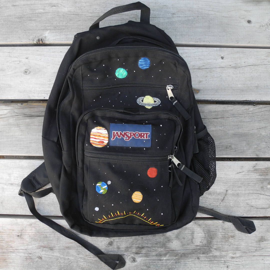 black jansport backpack with the solar system and stars embroidered