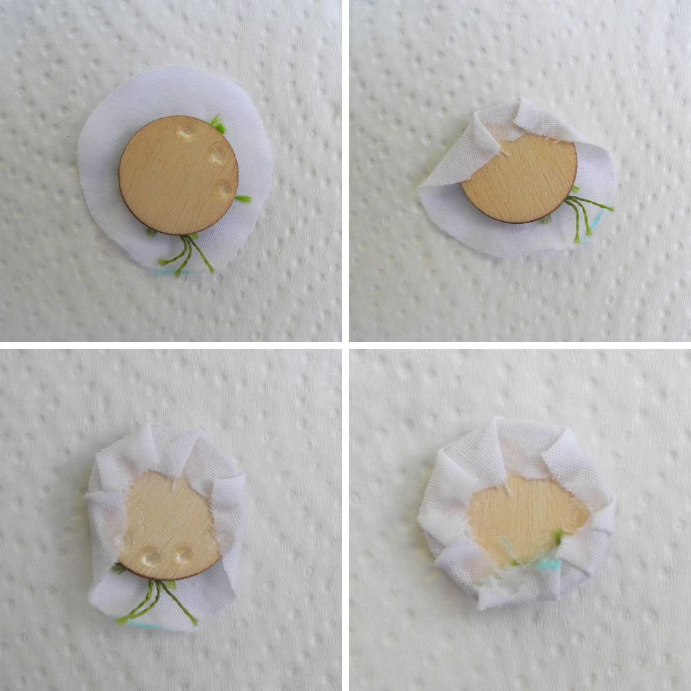 top left shows a wooden disc with three dots of clear glue on top of a white circle of fabric with green threads poking out. top right shows the same disc with some of the fabric glued over the edge. bottom left image shows more of the white fabric glued down with  more dots of glue on the uncovered edge of the wood disc. bottom right image shows the disc with all of the fabric glued around the edge. 