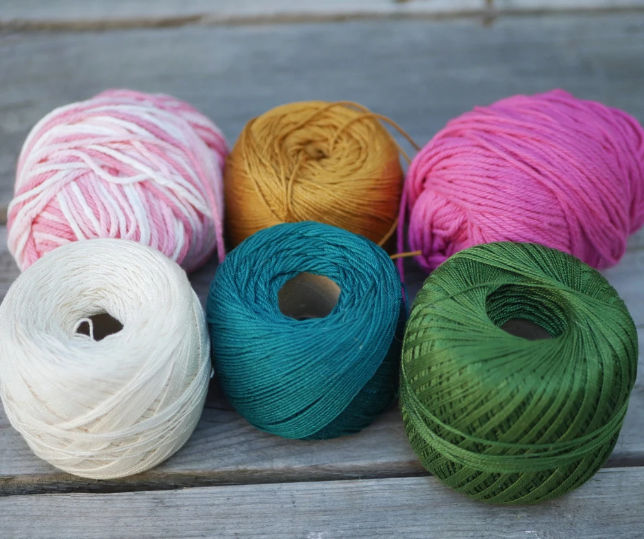 image shows an assortment of cotton yarns in assorted weights and colors. From top left going clockwise colors are pink and white, yellow, pink, white, teal, and green. 