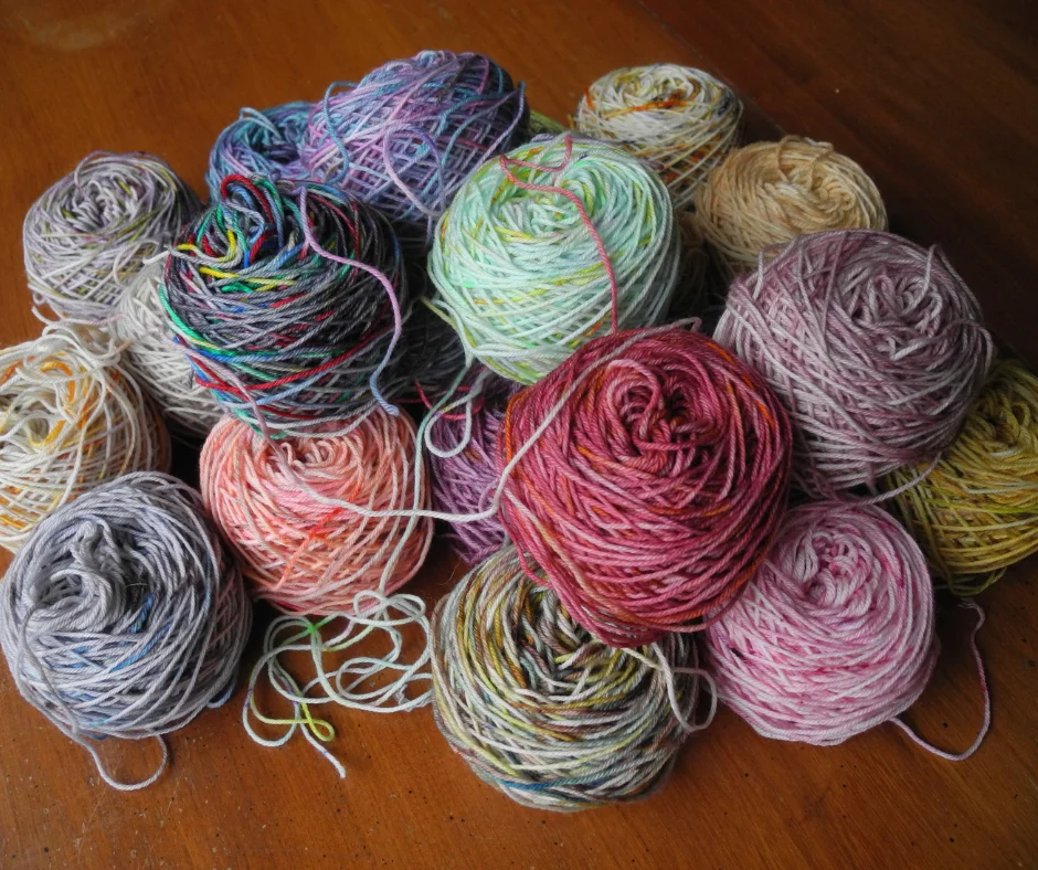 a large pile of caked up yarn in a variety of colors on a wood table. 