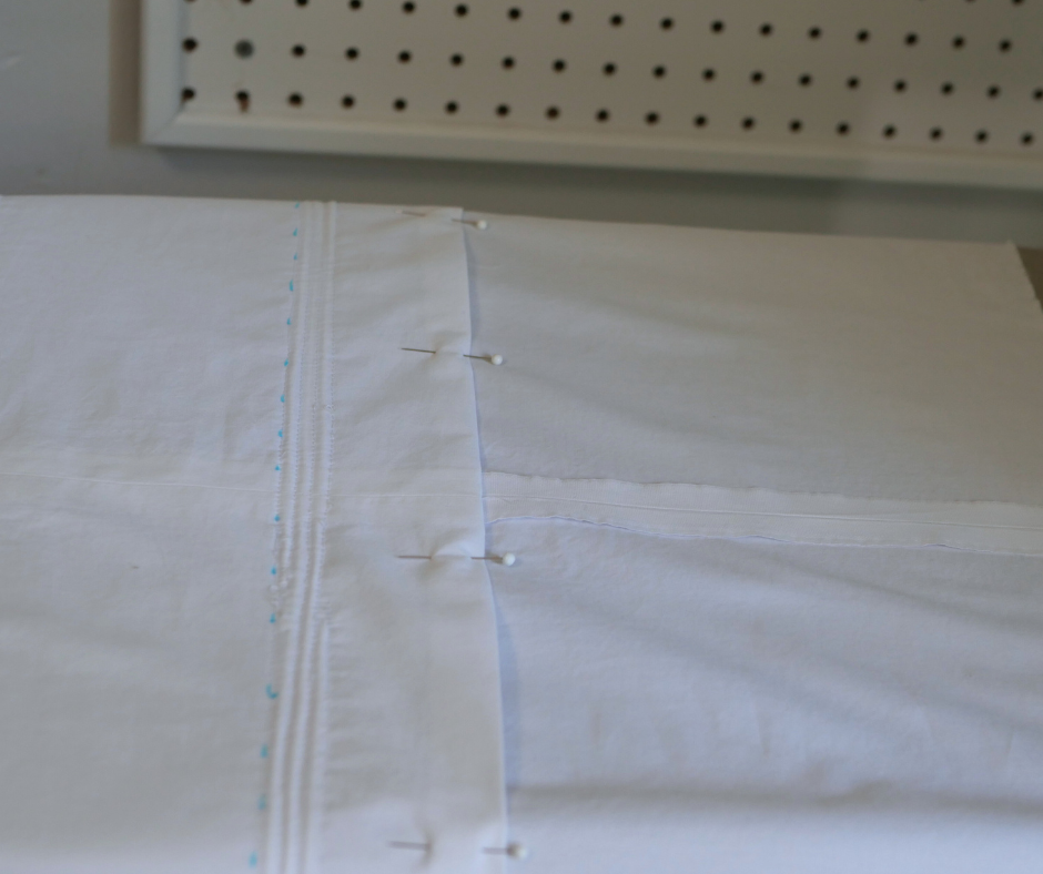 the upper edge of the inner layer of a white corded petticoat in pinned neatly to be ready for sewing. 