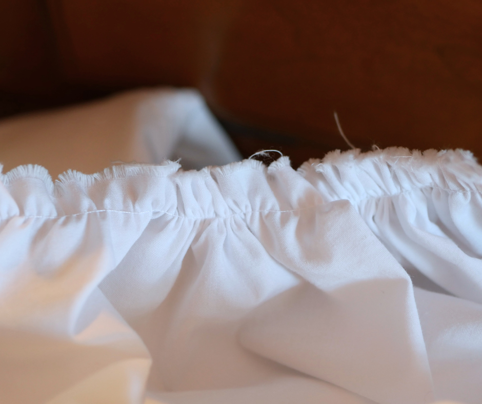 close up of white fabric machine gathered with slightly frayed edges