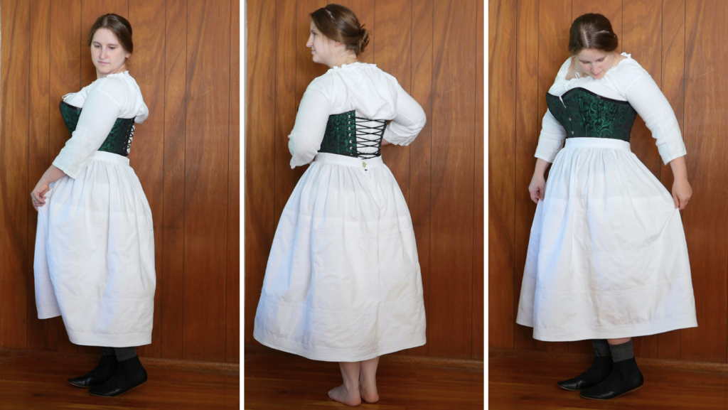 three pictures side by side of a white woman against a wood panel background wearing a white chemise, green and black corset, and a white corded petticoat. Left image shows woman from the left side, middle image shows the back, and right image shows three quarter facing to the front. 