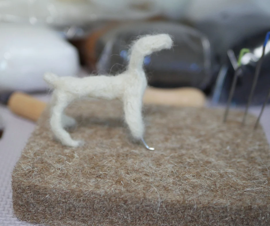 a vaguely dog shaped sculpture out of white wool with some metal wire sticking out. 