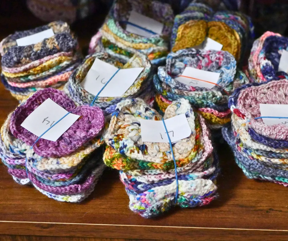 stacks of multicolor crochet squares each rubber-banded together with a different number on top of each stack. 