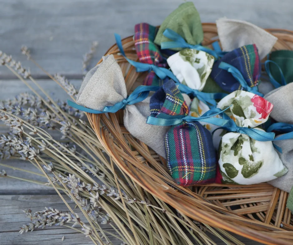 basket of fabric bags with different patterns all tied shut with a blue ribbon. dried lavender lays in front of the basket. 