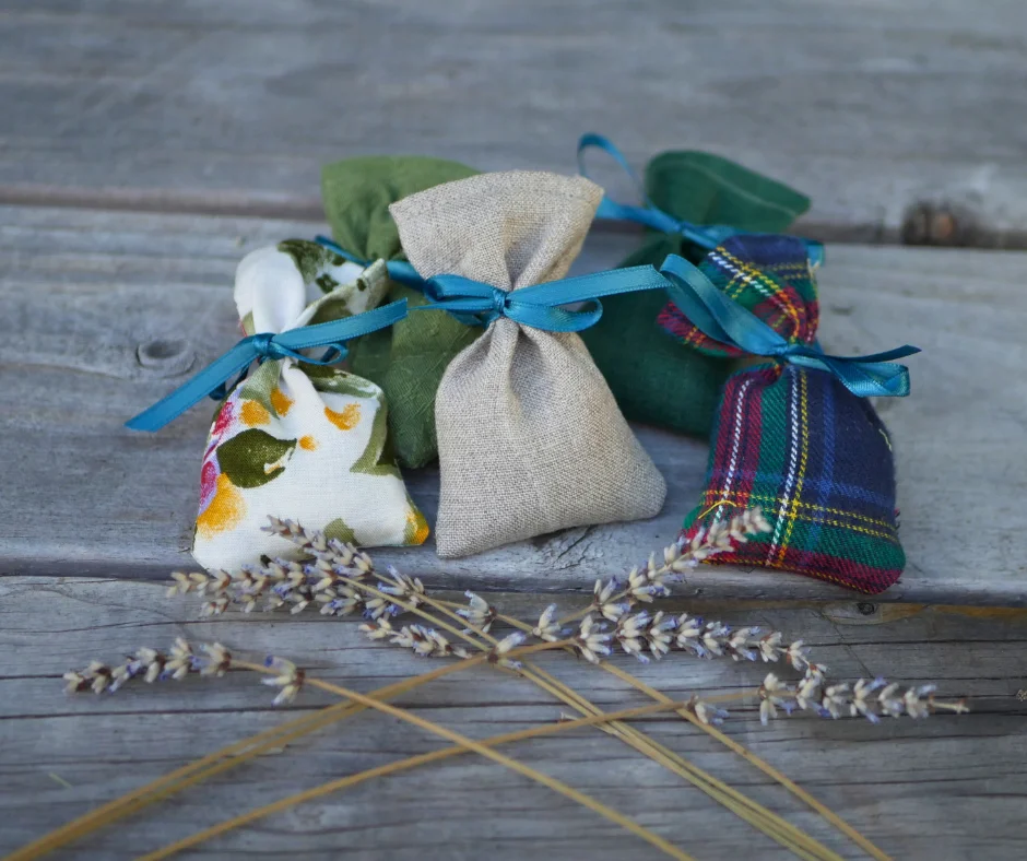 five bags made of different fabrics each tied shut with a blue ribbon. dried lavender flowers can be seen in the foreground. 