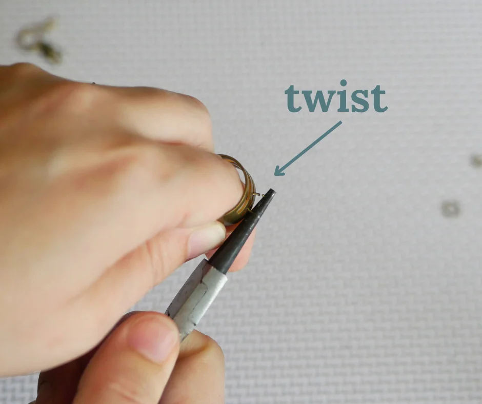 Image of a pair of white hands opening a jump ring with a jump ring opener and a pair of round nose pliers. The image is labeled twist. 