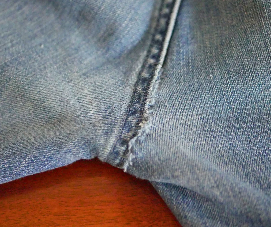 Image shows the crotch seam of a pair of jeans that has been repaired. There is a visible line of stitching but it is subtle. 