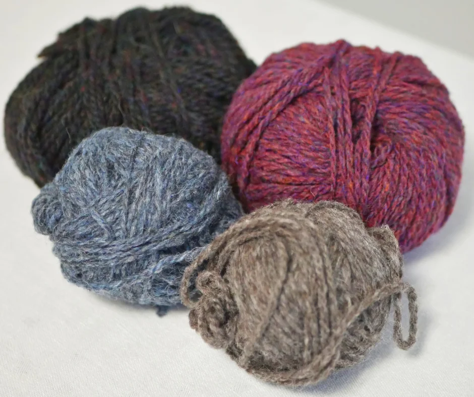 Image of four balls of yarn with heathered colorways in black, red, blue, and grey. 