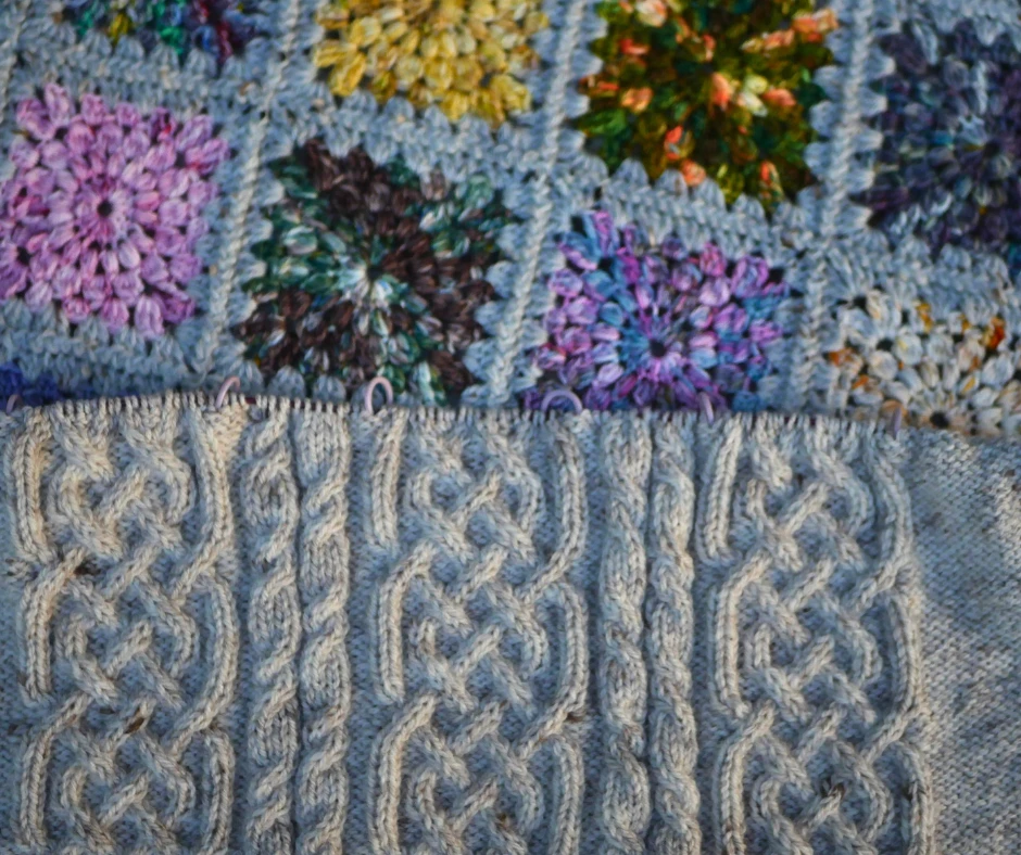 Image of cream colored cable knit fabric on top of a multicolored granny square blanket. 