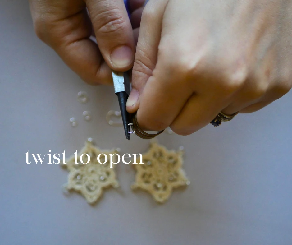 Image of a pair of white hands opening a jump ring by twisting with a pair of pliers and a jump ring opener. Text reads twist to open. 