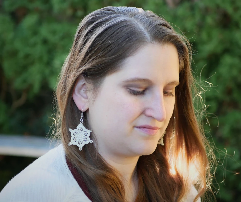 Image of a white woman with light brown hair. She is wearing crochet snowflake earrings.