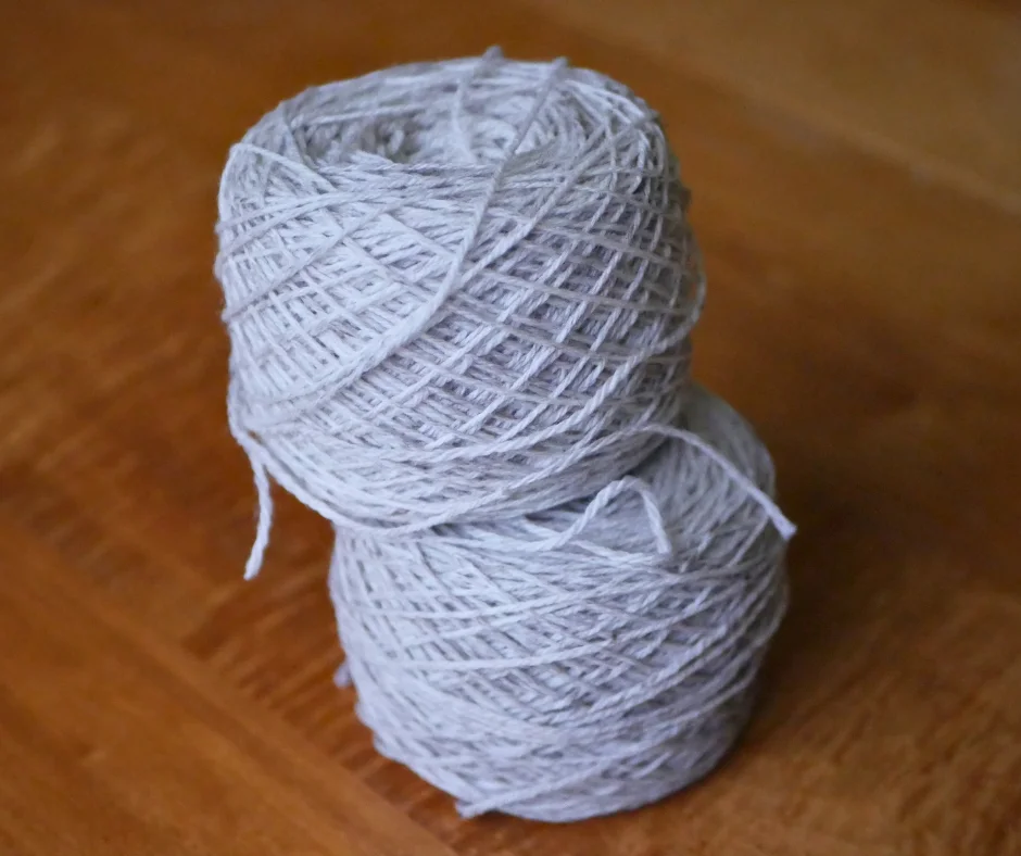 Image of two cakes of cream yarn stacked on top of each other. 