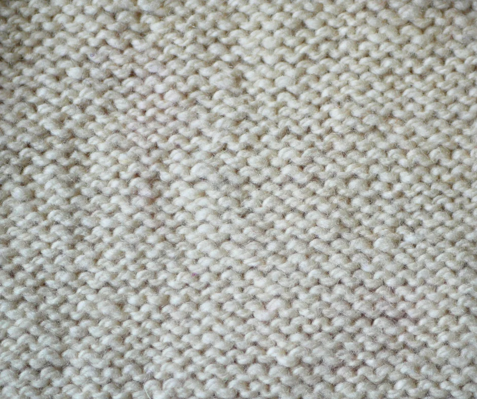 Image of white knit fabric in reverse stockinette stitch. 