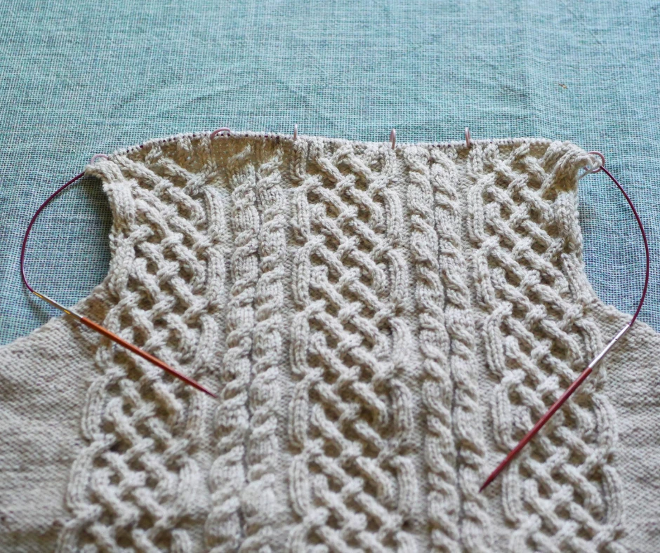 Image of the back of a cable knit sweater in process. 