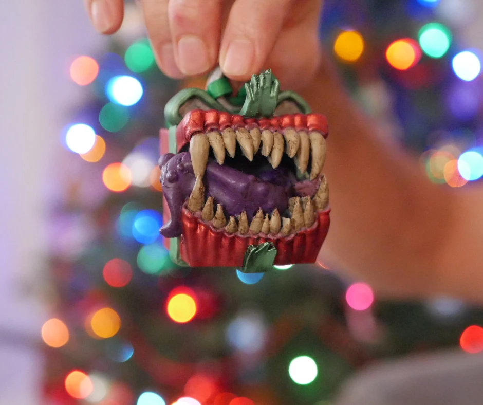 Image of a Dungeons and Dragons mimic, which looks like a red package with green ribbon and large pointy teeth and a purple tongue. 