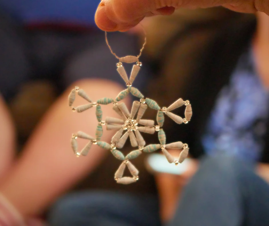 Image of a snowflake ornament made of wire and a mix of glass and paper beads. 