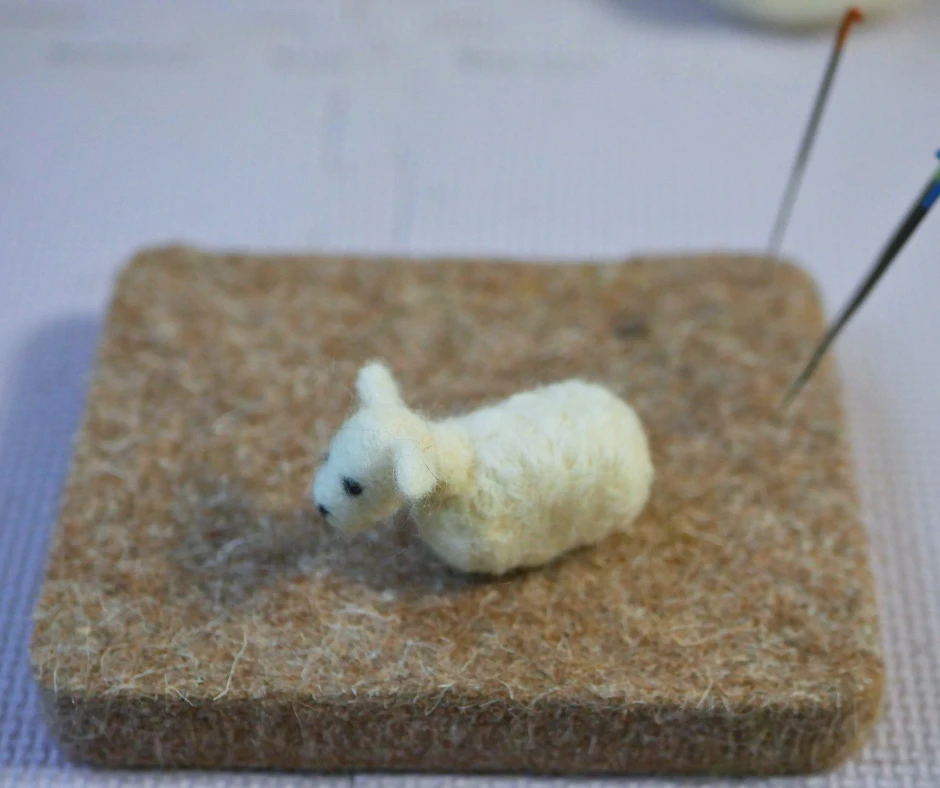 Image of a needle felted sheep without legs. 
