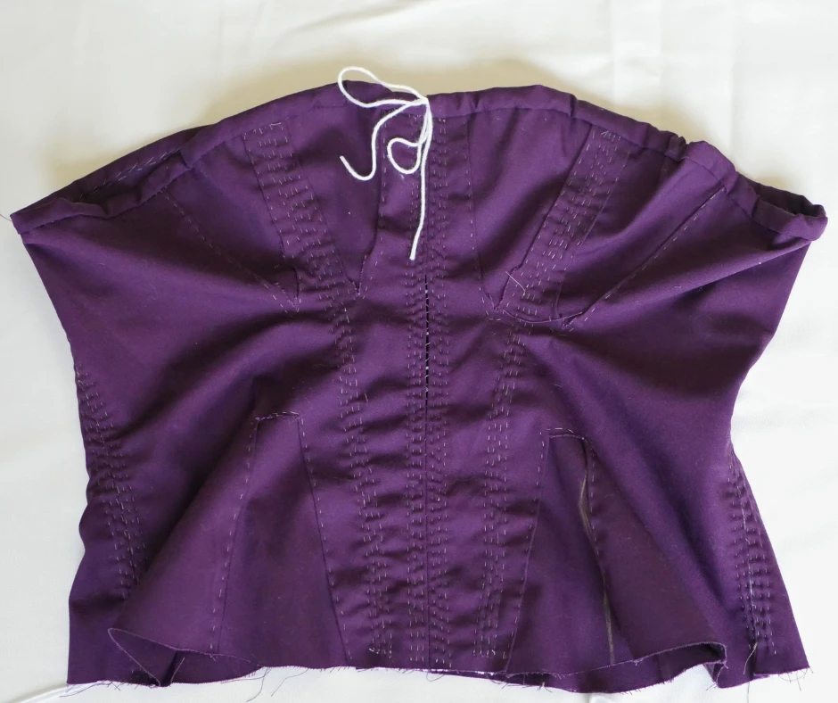 Image of a purple corded corset with white drawstring at the bust. 
