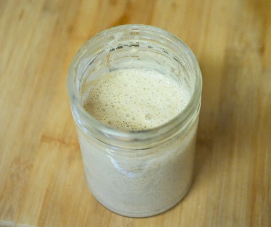 Image of a jar of sourdough starter full of bubbles. 