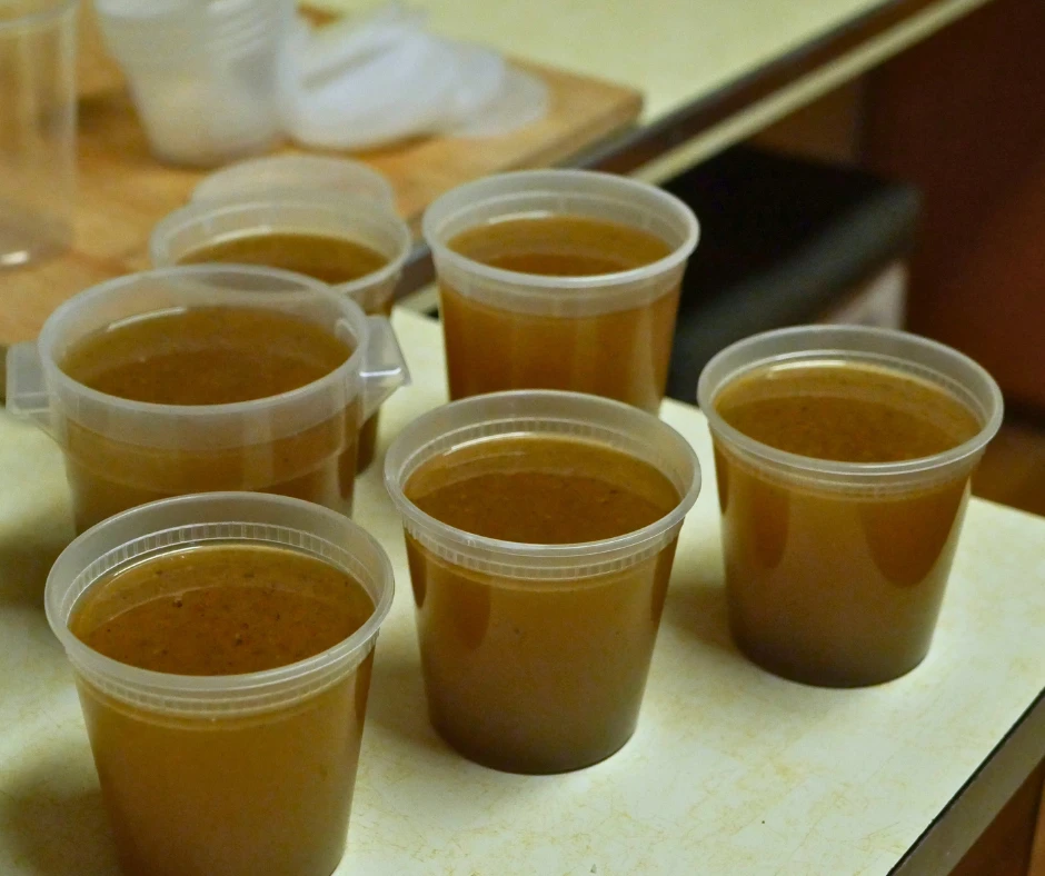 Image of six plastic containers in different sizes full of homemade broth. 