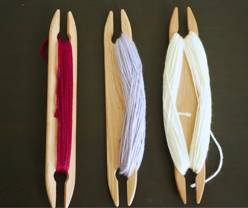 Image of three shuttles with yarn wrapped around it in different ways. The left shuttle has the yarn wrapped around the middle, the middle shuttle has the yarn wrapped in a figure eight around one side, the right shuttle has yarn wrapped in a figure eight around both sides. 