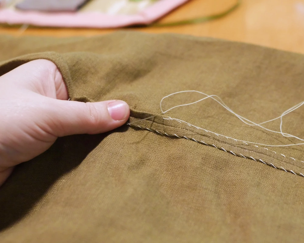 A close up of sewing down raw edges with a whip stitch. 