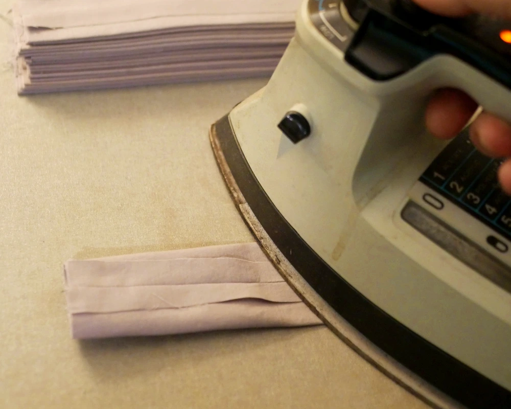 A curtain tab being ironed so that the seam in the center and the raw edges are open. 