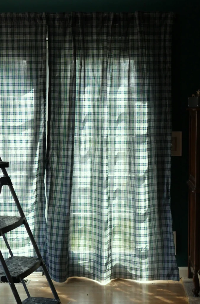 Green and gray plaid curtains being hung up. 